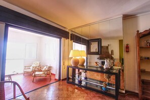 A spacious room with a glass console table, wicker chairs, and a large mirror.