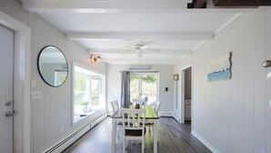 Ein Essbereich mit Tisch, Stühlen, Deckenventilator und Blick ins Freie.