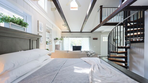 Ein Schlafzimmer mit einem großen Bett, einer Holztreppe und Blick ins Freie.