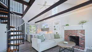 Ein geräumiges Wohnzimmer mit einem weißen Sofa, einem Kamin und einer Holztreppe.