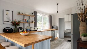 A modern kitchen with a wooden island, stainless steel appliances, and a large window. - Hilltop Hideaway, Firepit, Starry Nights & Privacy (Mullamuddy)