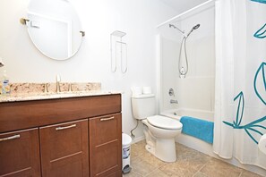 Een bad/douchecombinatie, een bubbelbad, een haardroger, handdoeken
