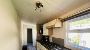 Una cocina compacta con estufa a gas, un lavamanos, un microondas y armarios de madera.
