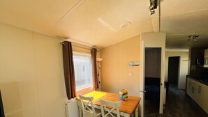 Habitación compacta con mesa de comedor, sillas, radiador y ventana con cortinas.