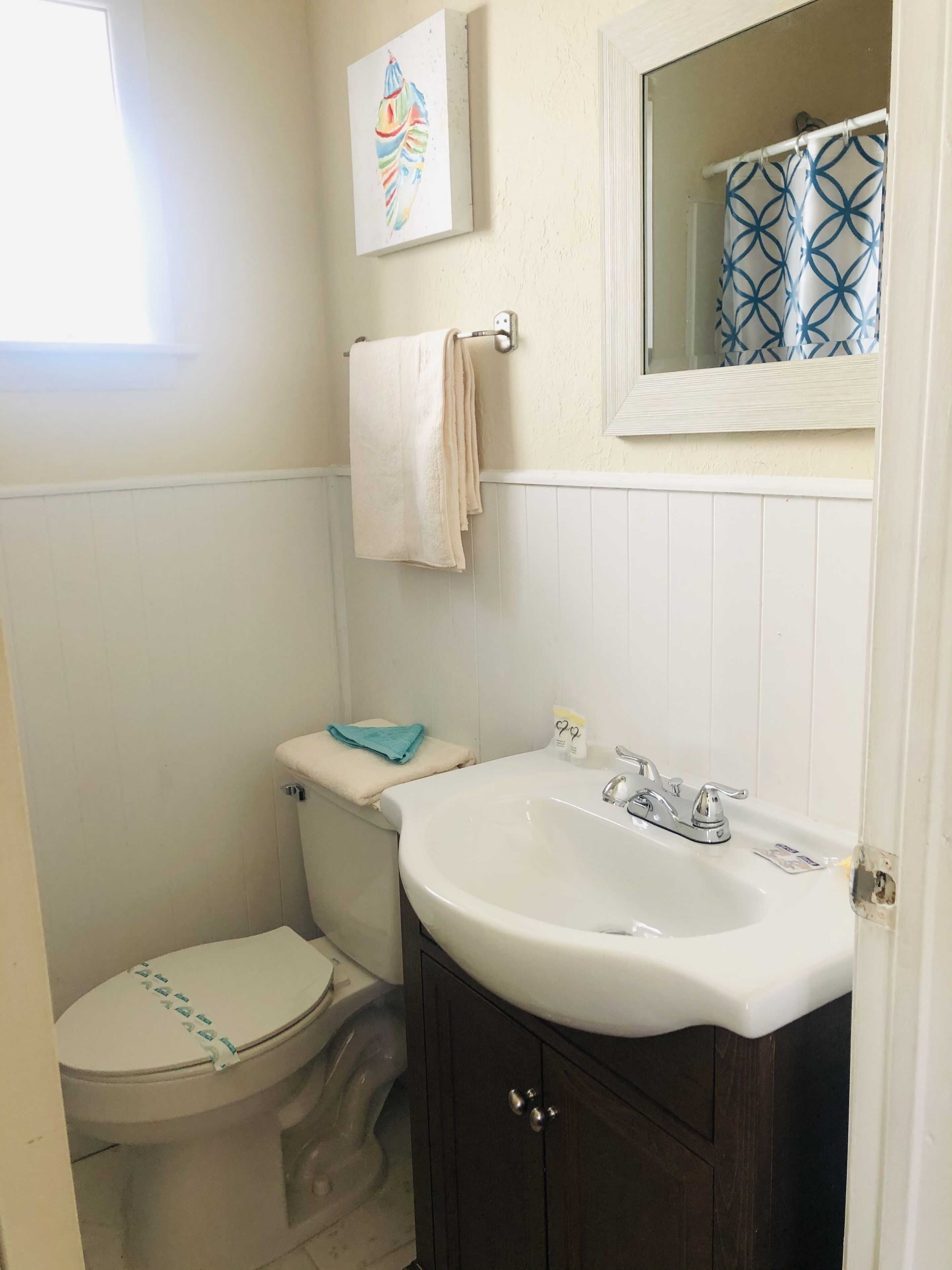 A small bathroom with a toilet, sink, and a mirror above the sink.