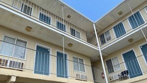 Un edificio de varios pisos con balcones, ventanas y un extintor visible.