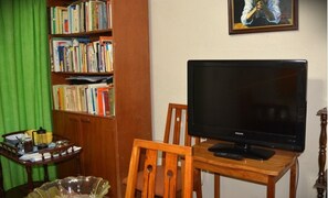 Relax in this cozy space with a bookshelf filled with books, a TV, and a comfortable chair.