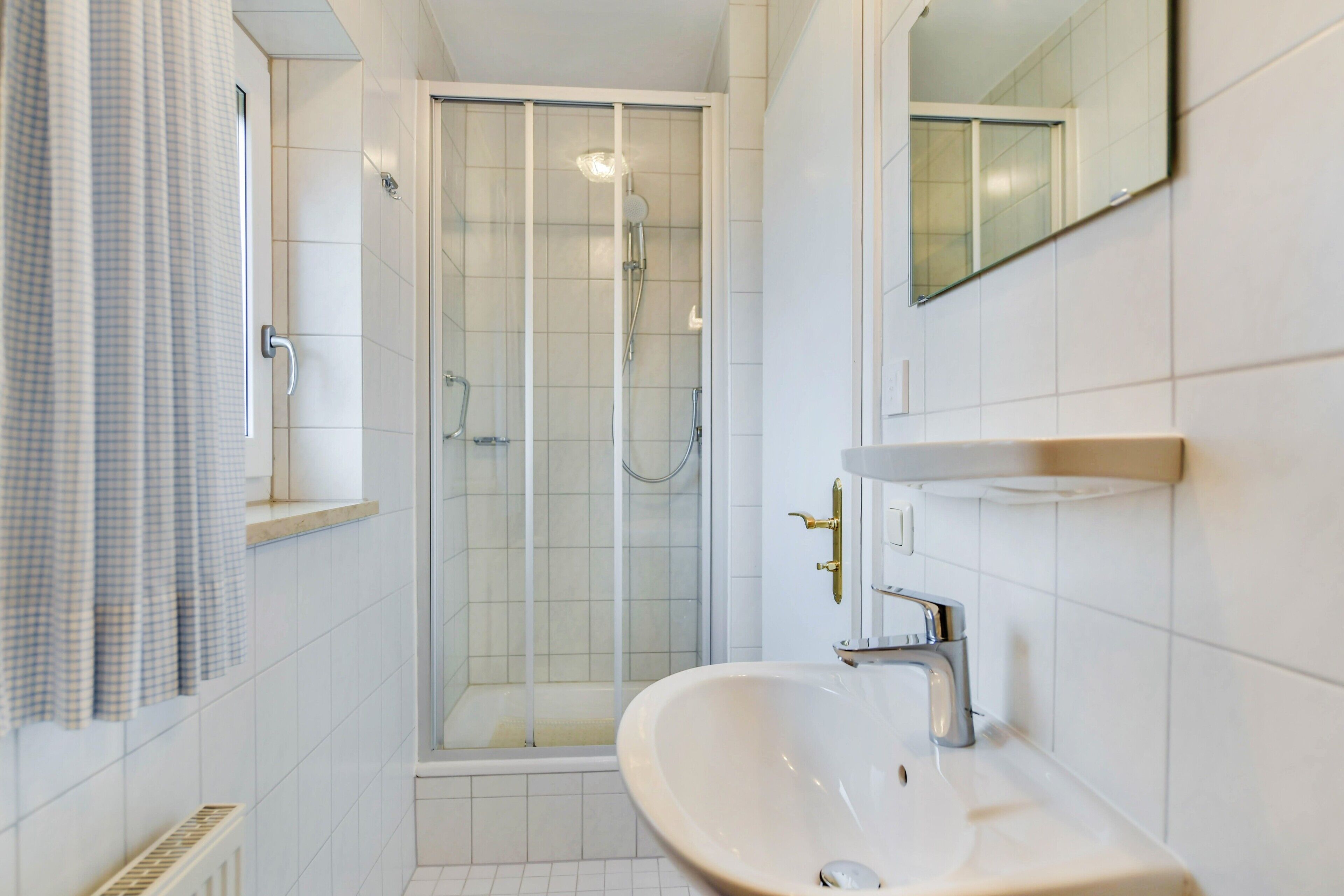 Une salle de bain moderne avec une douche à parois de verre, un lavabo avec un miroir et un porte-serviettes.