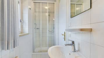 Une salle de bain moderne avec une douche à parois de verre, un lavabo avec un miroir et un porte-serviettes.