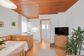 A compact living space with a dining area, kitchenette, and a television.
