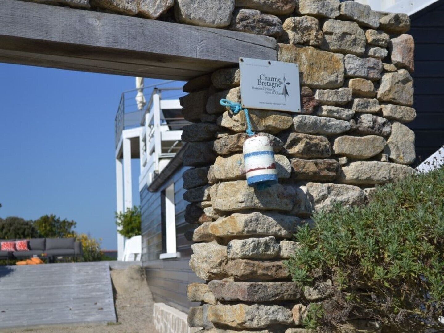 Eine Steinsäule mit einem Schild, auf dem "Charme Bretagne" steht, und einem maritimen Schmuckstück.