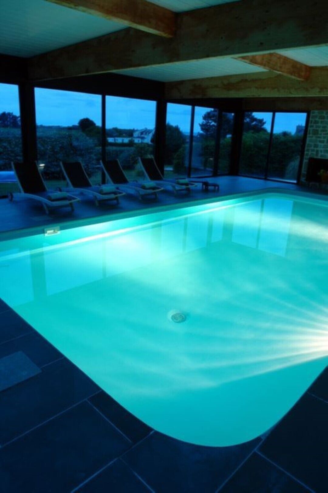 A swimming pool with lounge chairs and a view of the outdoors.