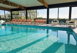 A swimming pool with sun loungers and a view of the outdoors.