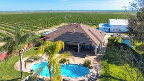 Propiedad residencial con piscina, paneles solares y un gran campo al fondo.