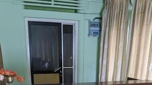 A reception desk in a room with a tiled floor, a window with curtains, and a wall-mounted air conditioning unit.