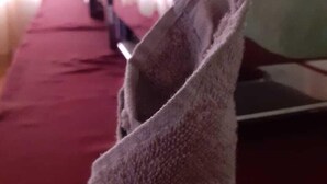 A room with a red carpet, a laptop on a table, and a folded towel on the floor.
