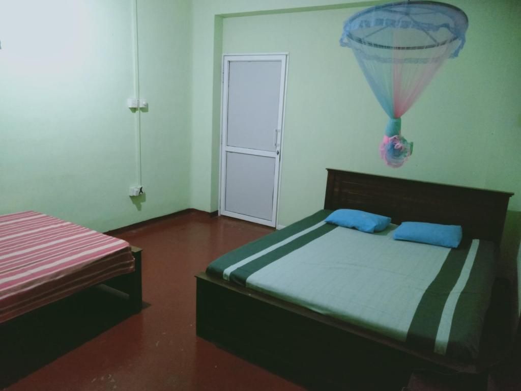 A room with two beds, one with a striped bedspread and the other with a solid bedspread and two pillows.