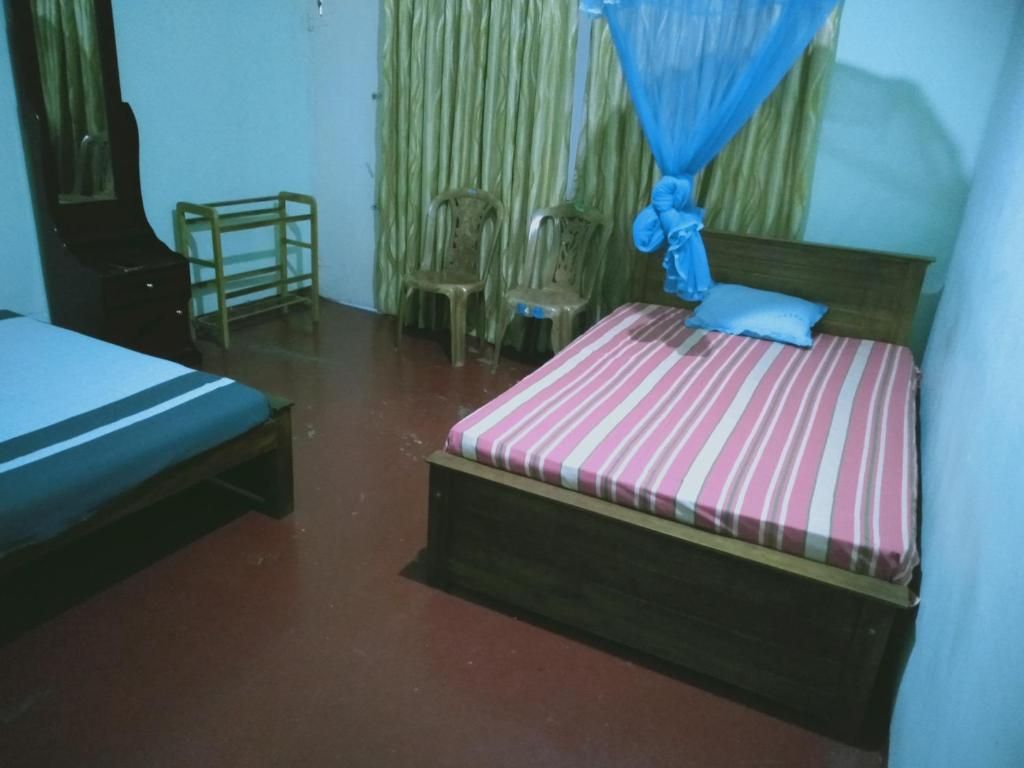 A room with a bed, a chair, a small table, and a mosquito net.