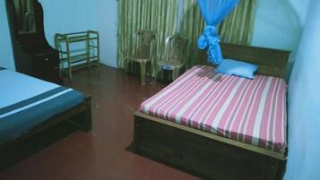 A room with a bed, a chair, a small table, and a mosquito net.