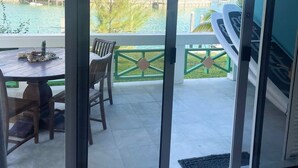 Una stanza con una porta scorrevole in vetro che dà su un balcone con vista su una piscina e degli edifici.
