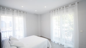 A bedroom with a bed, white curtains, and a balcony view. - Cubo's Apartamento Tivoli B3 / free wifi / air conditioning (Benalmádena)