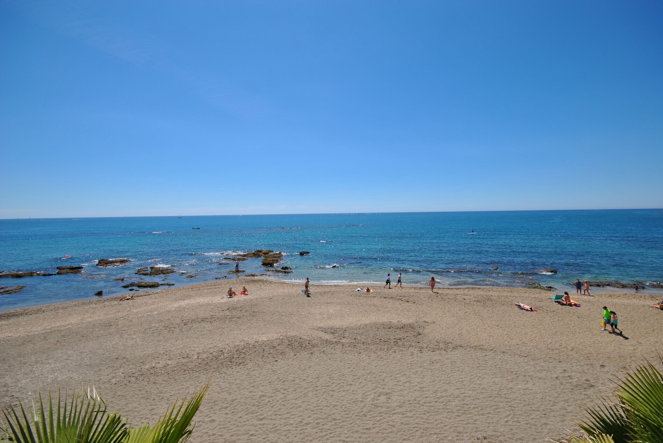 Una playa con cielos despejados y aguas tranquilas.