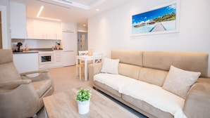 A modern living room with a beige sofa, a coffee table with a plant, and a dining area with a white table and chairs. - Cubo's Apartamento Tivoli B3 / free wifi / air conditioning (Benalmádena)