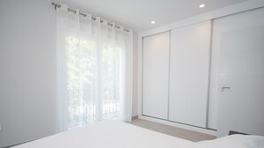 A bedroom with a large bed, a sliding door closet, and a window with sheer curtains. - Cubo's Apartamento Tivoli B3 / free wifi / air conditioning (Benalmádena)