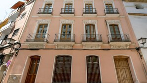 Un immeuble à plusieurs étages, doté d’une façade rose, de nombreux balcons et de grandes fenêtres.