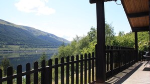 A wooden deck with a railing overlooking a lake and mountains. - Braeside by Interhome (Invergarry)