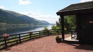A wooden cabin with a covered porch overlooking a lake and mountains. - Braeside by Interhome (Invergarry)