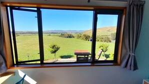 Una habitación con un ventanal que ofrece vistas a un campo verde y colinas distantes.