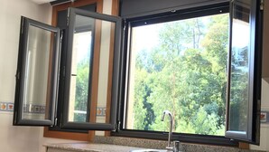 Eine Küche mit Geschirrspüler, Spüle und einem Fenster mit Blick auf Bäume.
