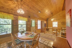 Une cabane en bois comprenant un coin repas, une cuisine et un balcon avec une balustrade.