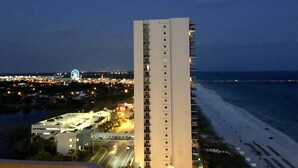 A high-rise hotel with multiple floors, a beach view, and a Ferris wheel in the background.