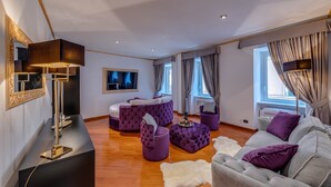 A modern living room with a grey sofa, purple ottomans, and a black console table. - SPANISH STEPS Extra Luxury Apartment (Roma)