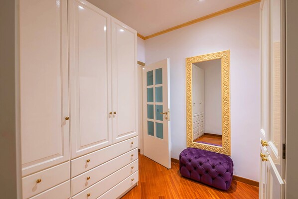 A hallway with a large wardrobe, a mirrored wardrobe, and a purple bench.
