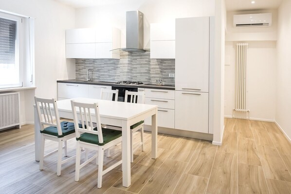 Una cocina moderna con armarios blancos, una estufa a gas y una ventana con persianas.