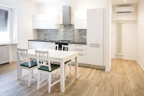 Moderni keittiö, jossa on valkoiset kaapit, kaasuliesi ja ikkuna, jossa on sälekaihtimet.