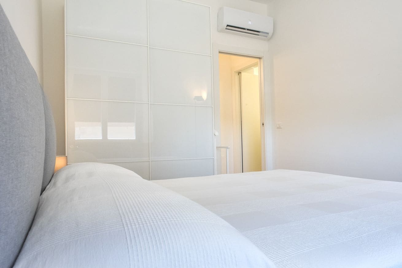 A hotel room with a bed, a wardrobe, and an air conditioning unit.