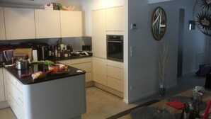 Una cocina moderna con armarios blancos, una isla central y una zona de comedor con una mesa redonda.