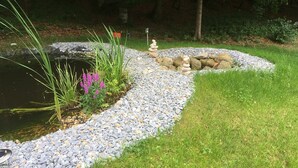 Un jardín con un estanque, piedras y plantas.