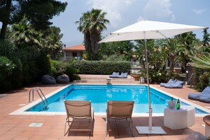 A swimming pool with lounge chairs and a sun umbrella, surrounded by palm trees and hedges. - A surrounded garden Villa, in the proximity of Catania and Etna (Mascalucia)