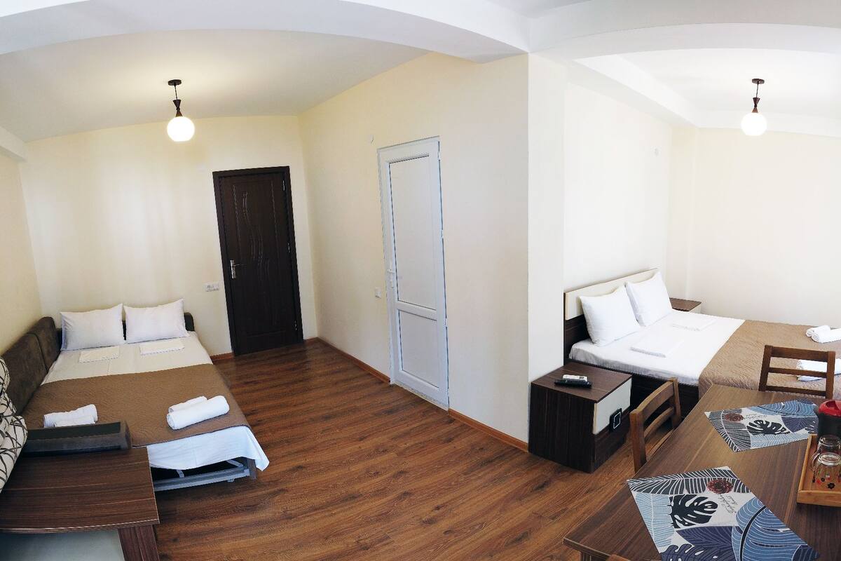 A hotel room with two beds, a desk, a chair, and a small table with a tray.