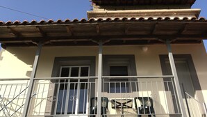 A building with a tiled roof, a balcony with a railing, and windows. - Taygetos (Sparta)