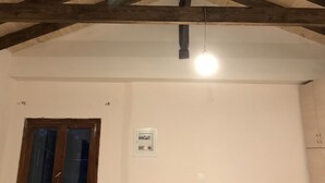 A room with a sloped wooden ceiling, a single window, and a light fixture. - Taygetos (Sparta)