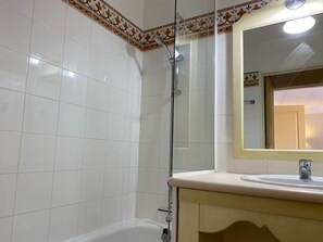 A bathroom with white tiled walls, a glass shower enclosure, a beige vanity with a mirror, and a white bathtub. - T3 cabin in Les Issambres with pool and parking (Les Issambres)