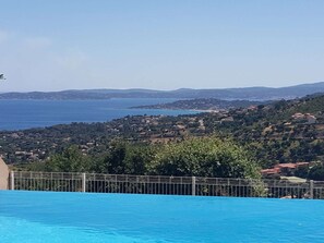 A pool with a view of a coastal town and hills in the background. - T3 cabin in Les Issambres with pool and parking (Les Issambres)