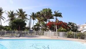 A clear blue pool with a white fence and palm trees in the background. - Duplex apartment located opposite the Golf de Saint-François.  (Saint-François)
