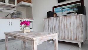 A kitchen with white cabinets, a wooden table, and a TV mounted on the wall. - Duplex apartment located opposite the Golf de Saint-François.  (Saint-François)